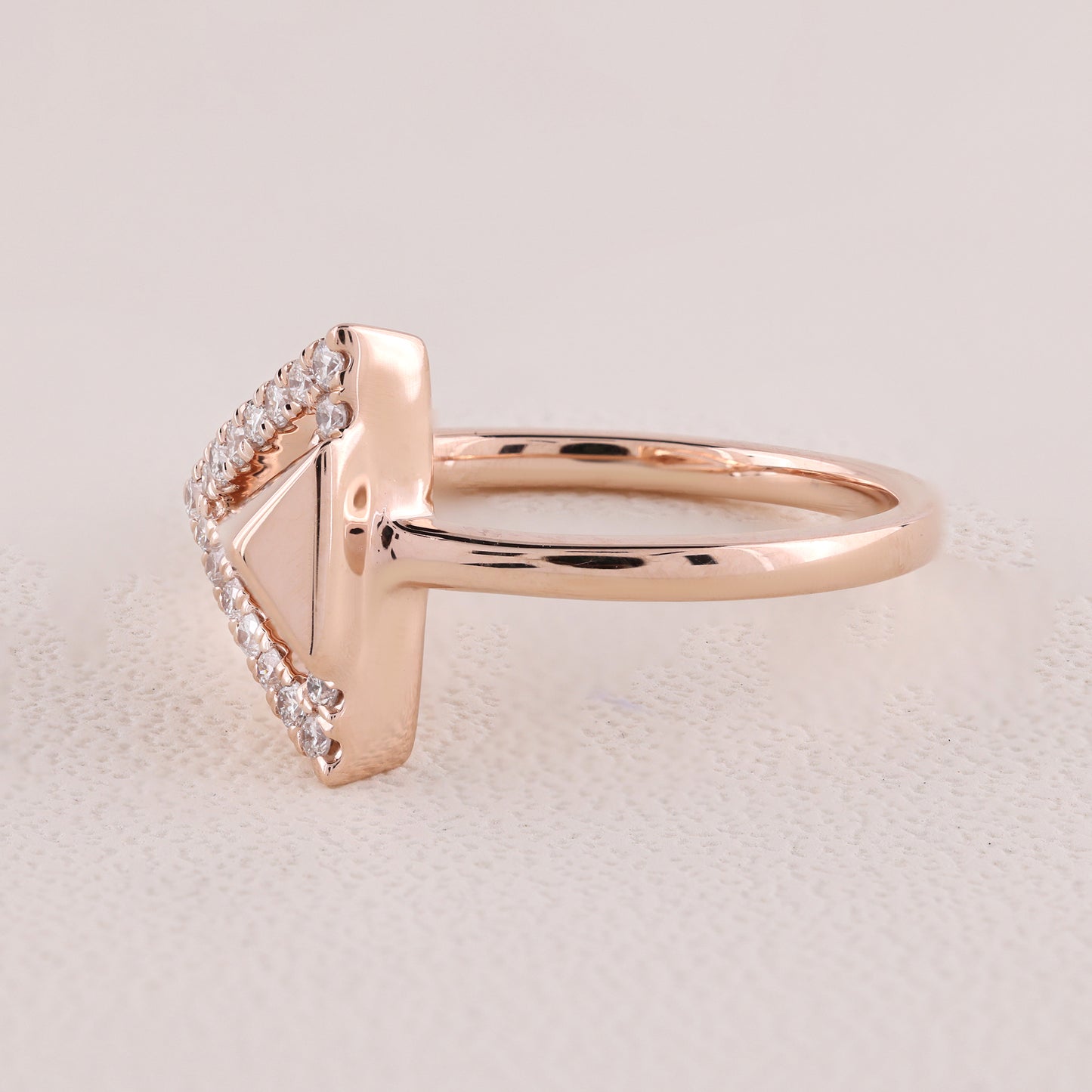 Rose gold ring with diamond accents on a light beige background