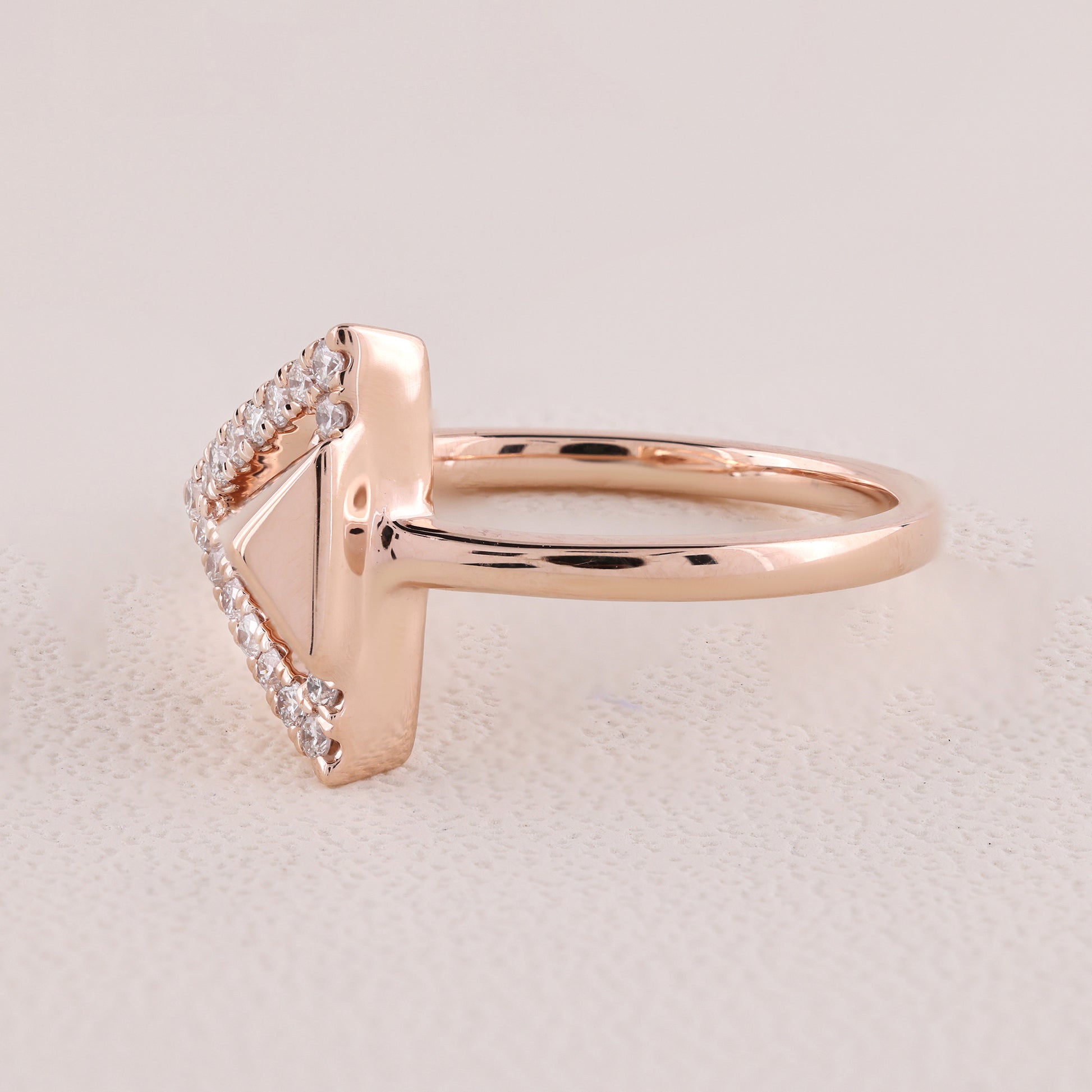 Rose gold ring with diamond accents on a light beige background