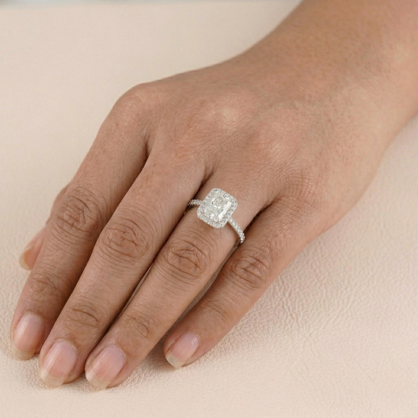 Diamond ring on a hand against a beige background