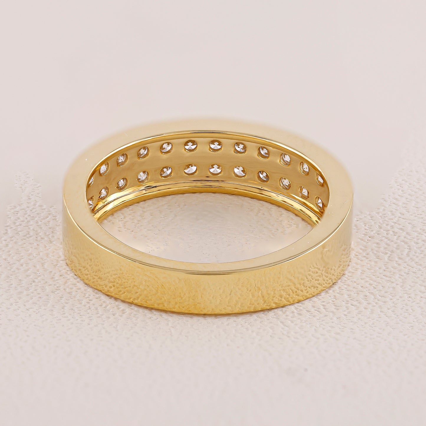 Gold ring with diamond accents on a light beige background