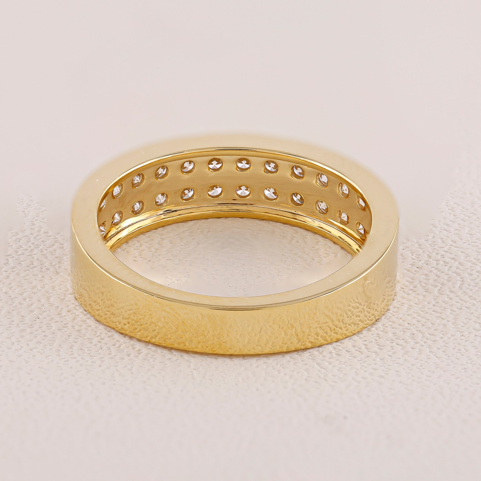 Gold ring with diamond accents on a light beige background
