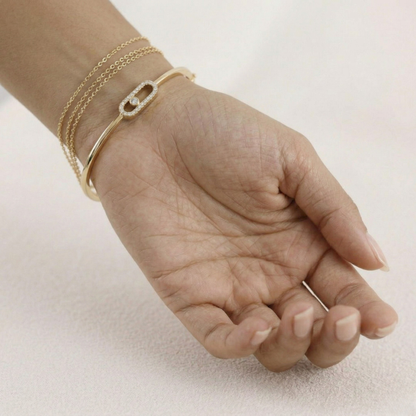 Hand wearing a gold bracelet on a light background