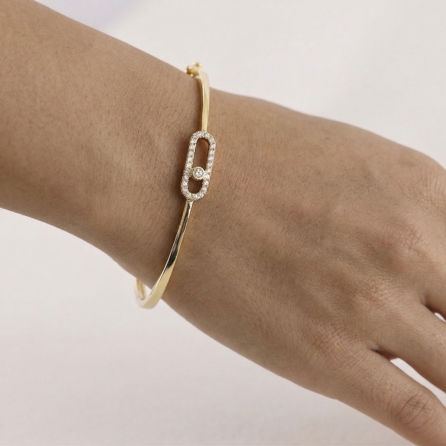 Gold bracelet with a diamond on a wrist against a light background