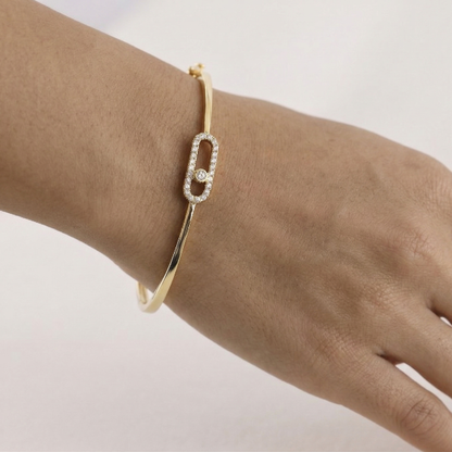 Gold bracelet with a diamond on a wrist against a light background