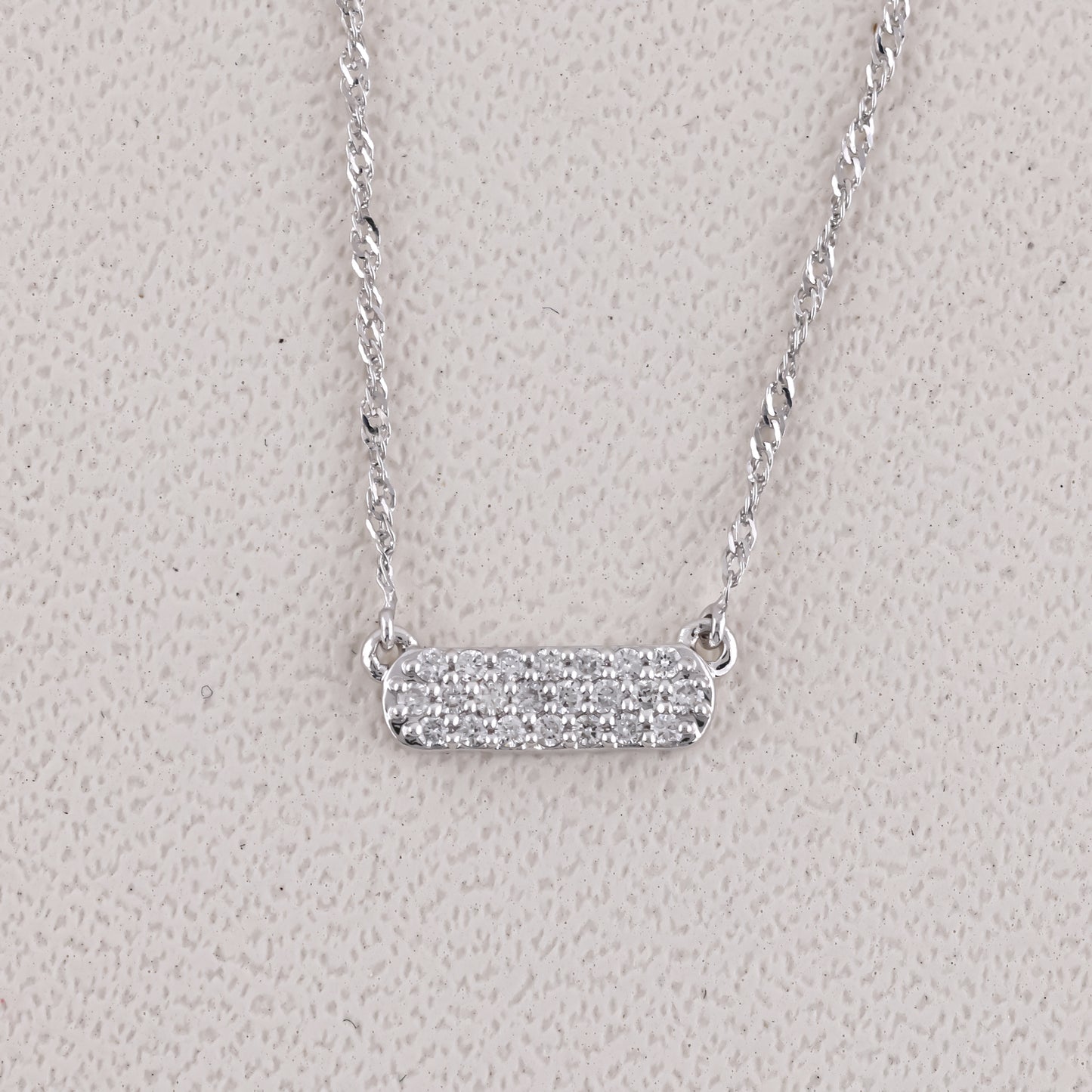 Silver necklace with a bar pendant on a light gray background