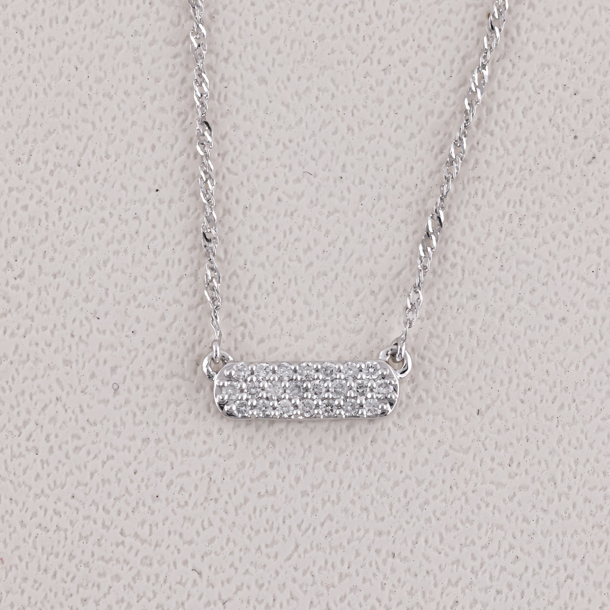Silver necklace with a bar pendant on a light gray background