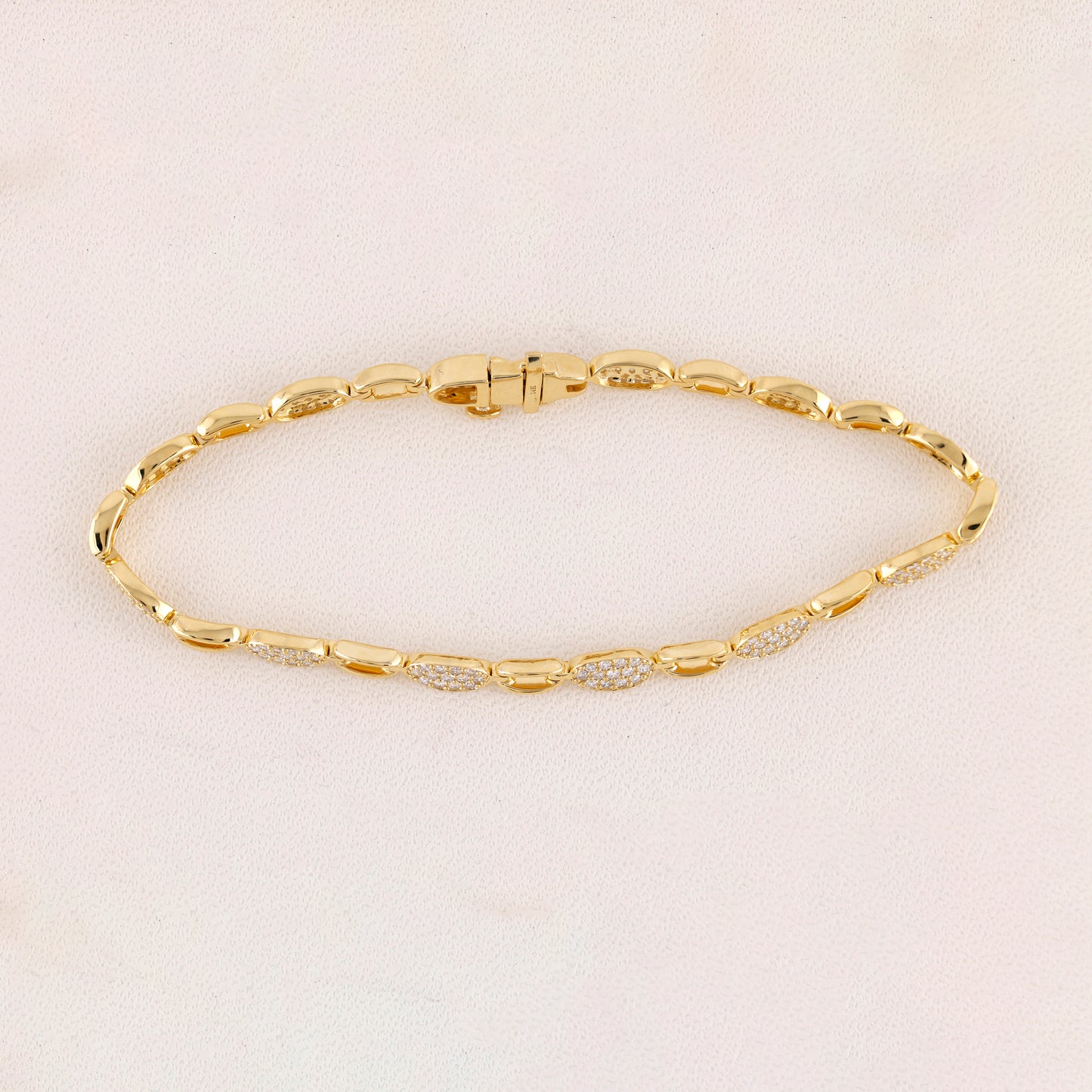 Gold bracelet with diamond accents on a light beige background