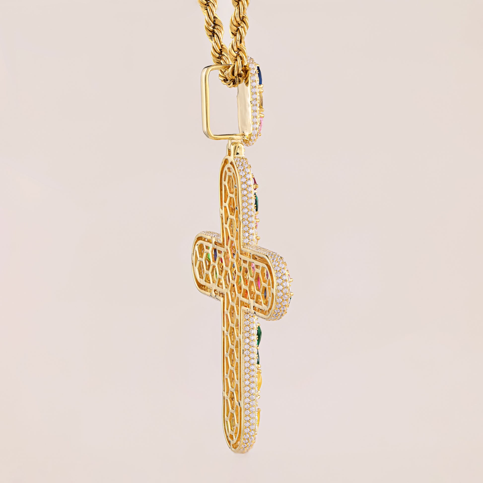 Gold cross pendant with intricate designs on a beige background