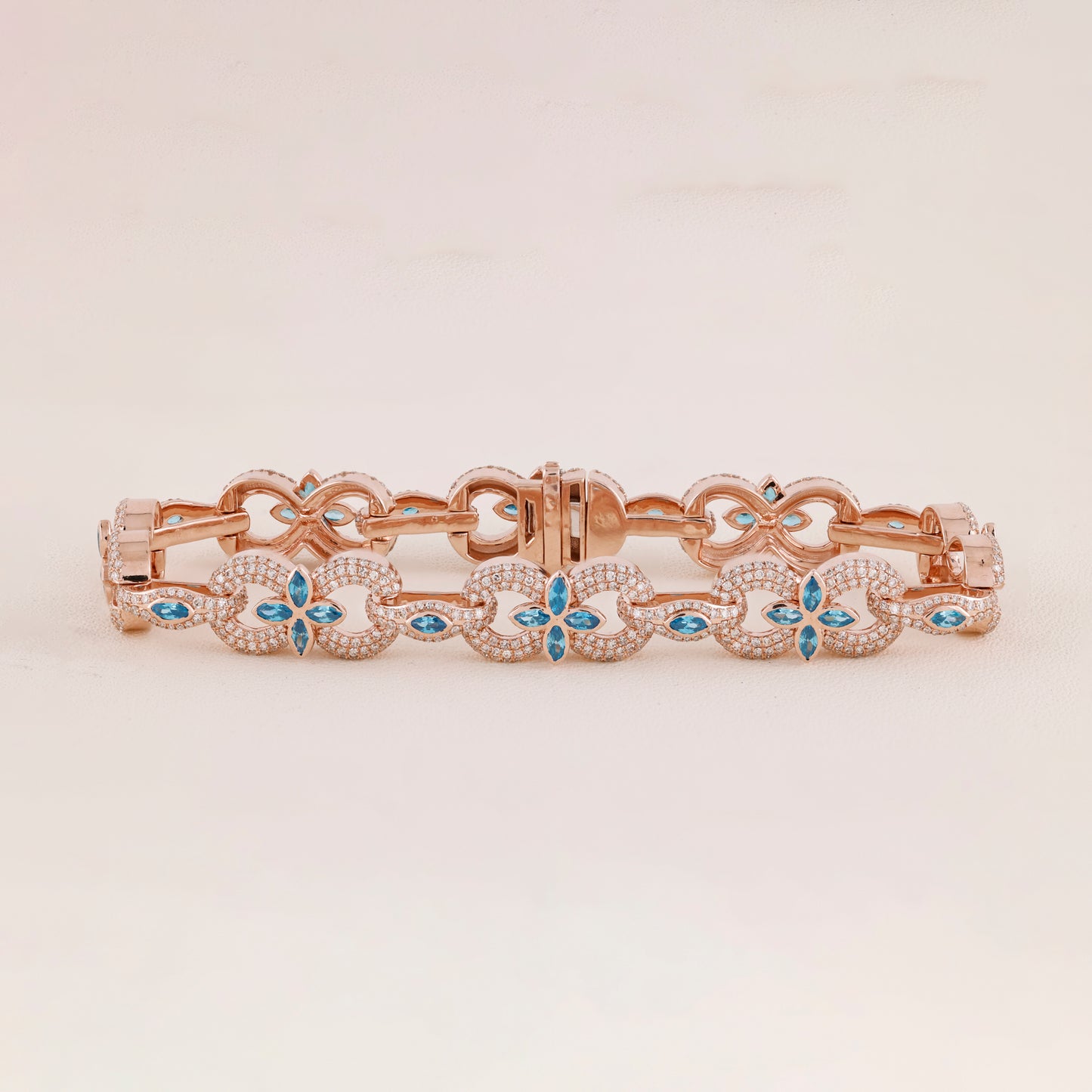 Rose gold bracelet with blue gemstones on a light beige background