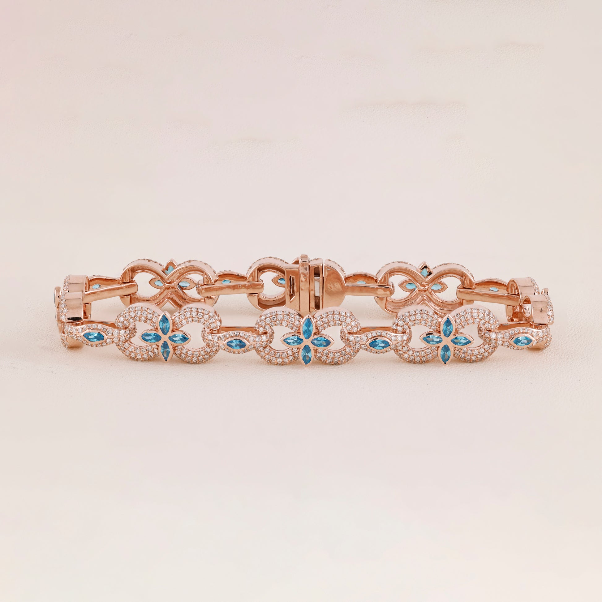 Rose gold bracelet with blue gemstones on a light beige background
