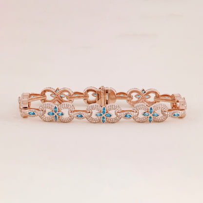 Rose gold bracelet with blue gemstones on a light beige background