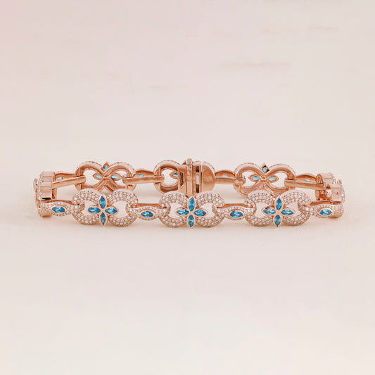 Rose gold bracelet with blue gemstones on a light beige background