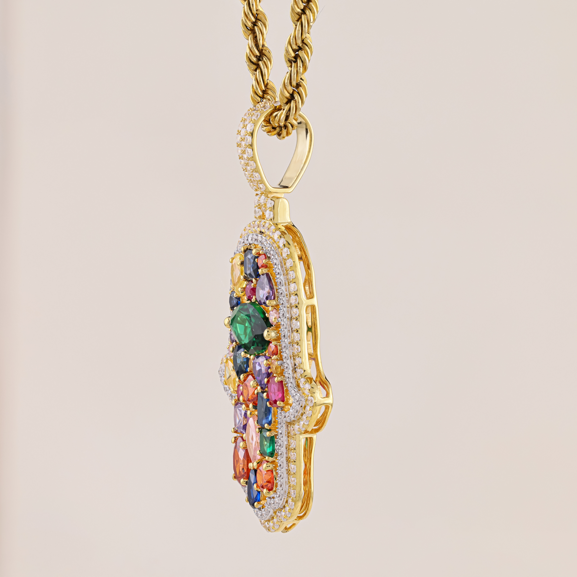 Gold pendant with colorful gemstones on a beige background