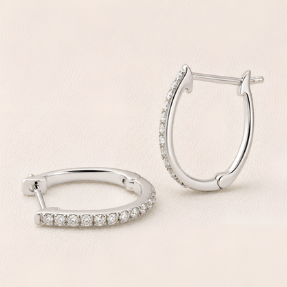 Pair of silver hoop earrings with embedded stones on a light beige background
