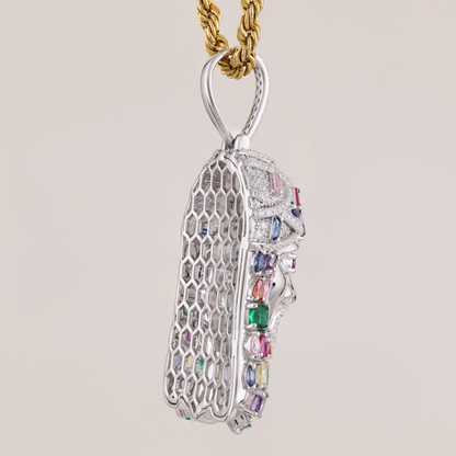 Silver pendant with colorful gemstones on a gold chain against a beige background