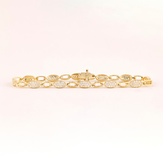 Gold bracelet with diamond accents on a light pink background