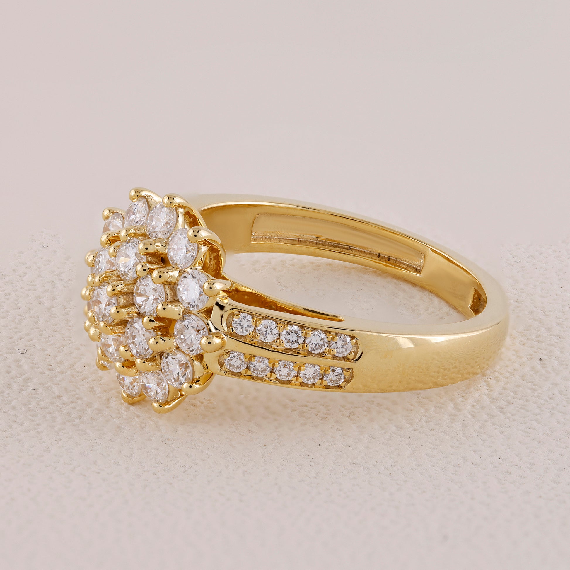 Gold ring with diamond cluster on a light beige background