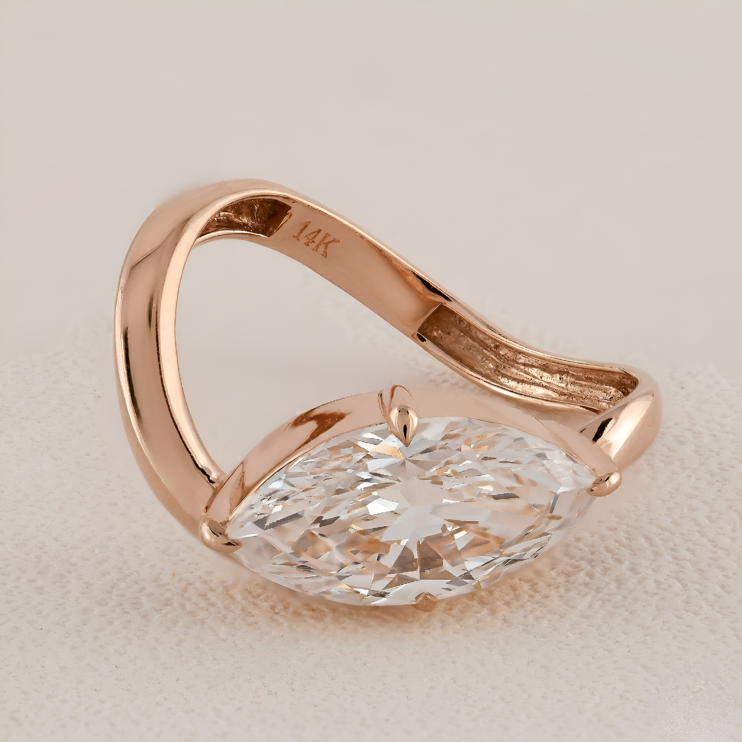 Rose gold ring with a large diamond on a beige background