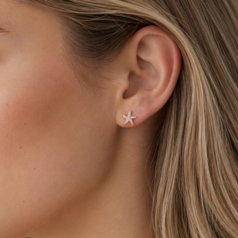 Starfish-shaped earring worn by a person with blonde hair.