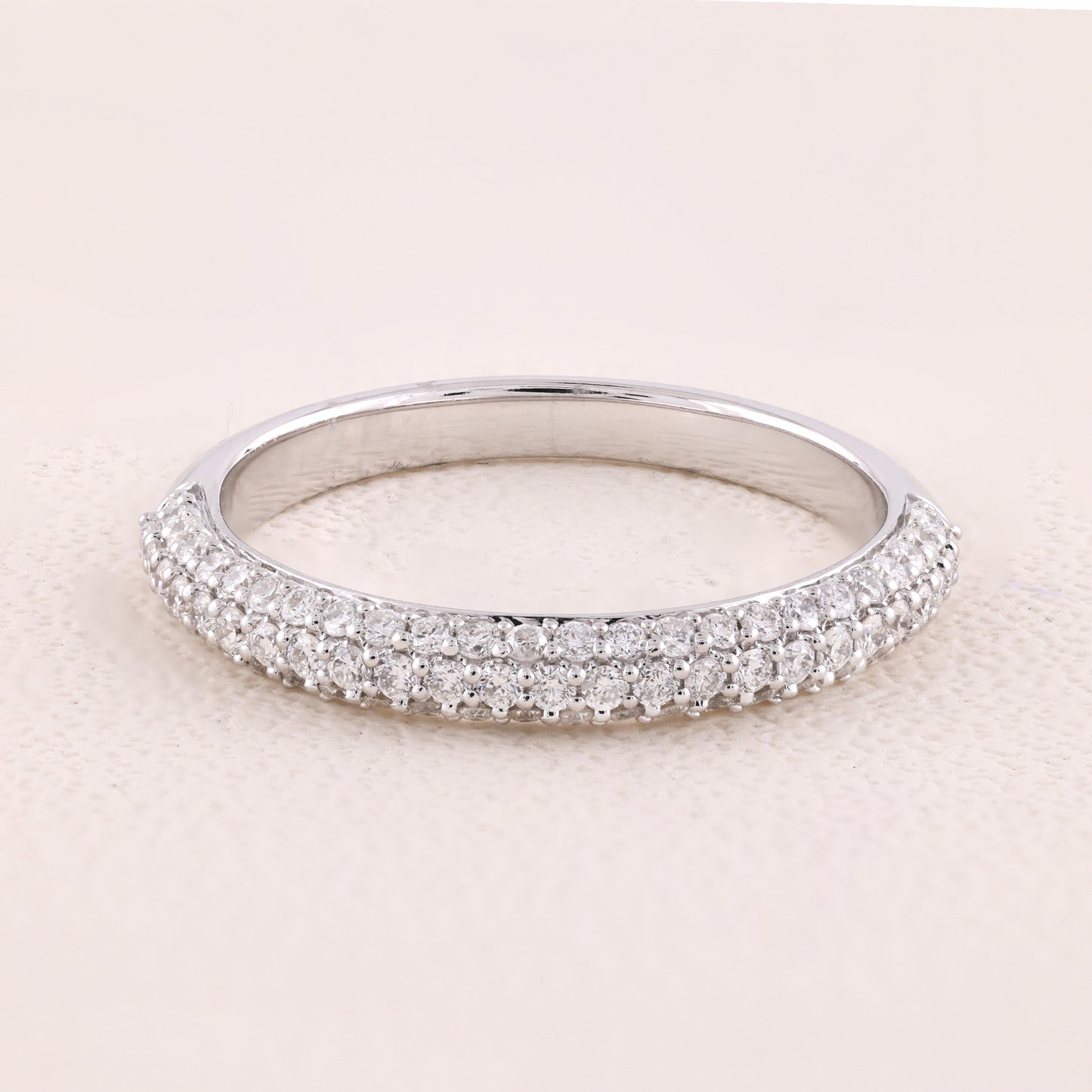 Silver ring with small diamonds on a light pink background