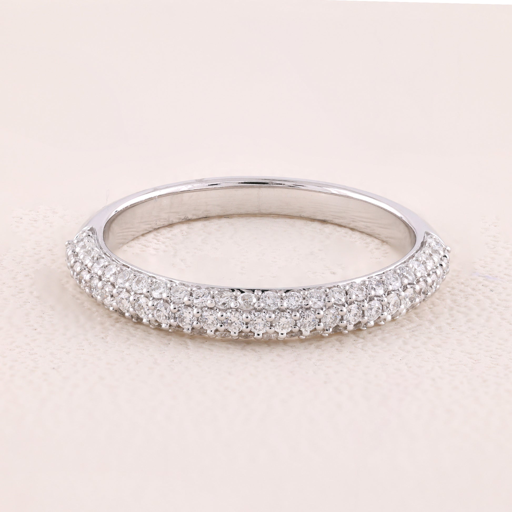 Silver ring with small diamonds on a light pink background
