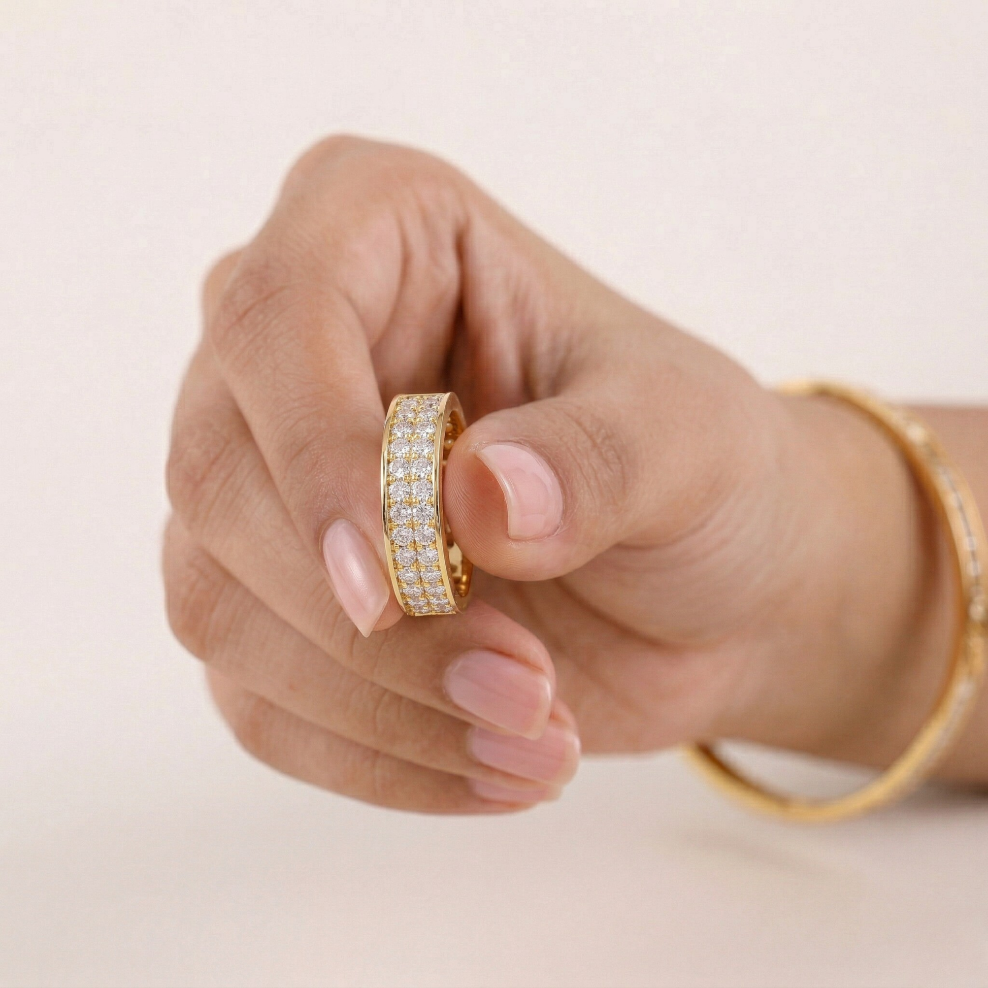 Hand wearing a gold ring with gemstones on a light background