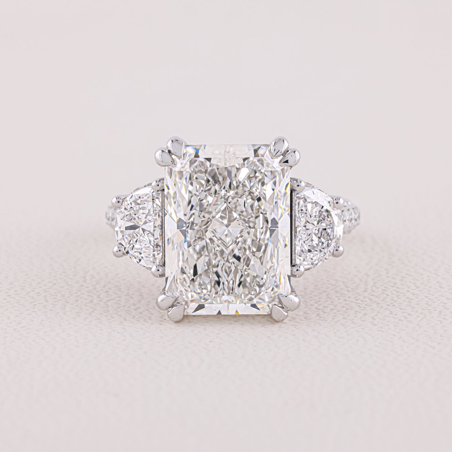 Diamond ring with a prominent central gemstone on a light gray background