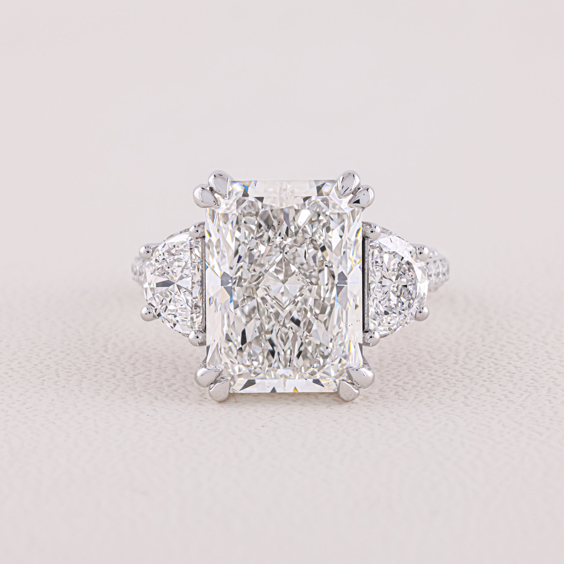 Diamond ring with a prominent central gemstone on a light gray background