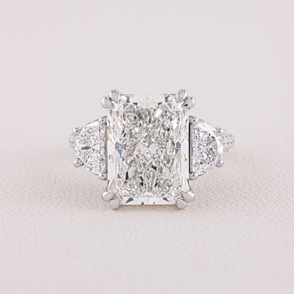 Diamond ring with a prominent central gemstone on a light gray background