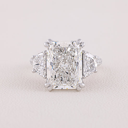 Diamond ring with a prominent central gemstone on a light gray background