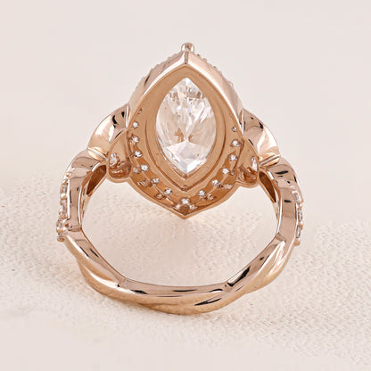 Rose gold ring with a pear-shaped diamond on a textured beige surface