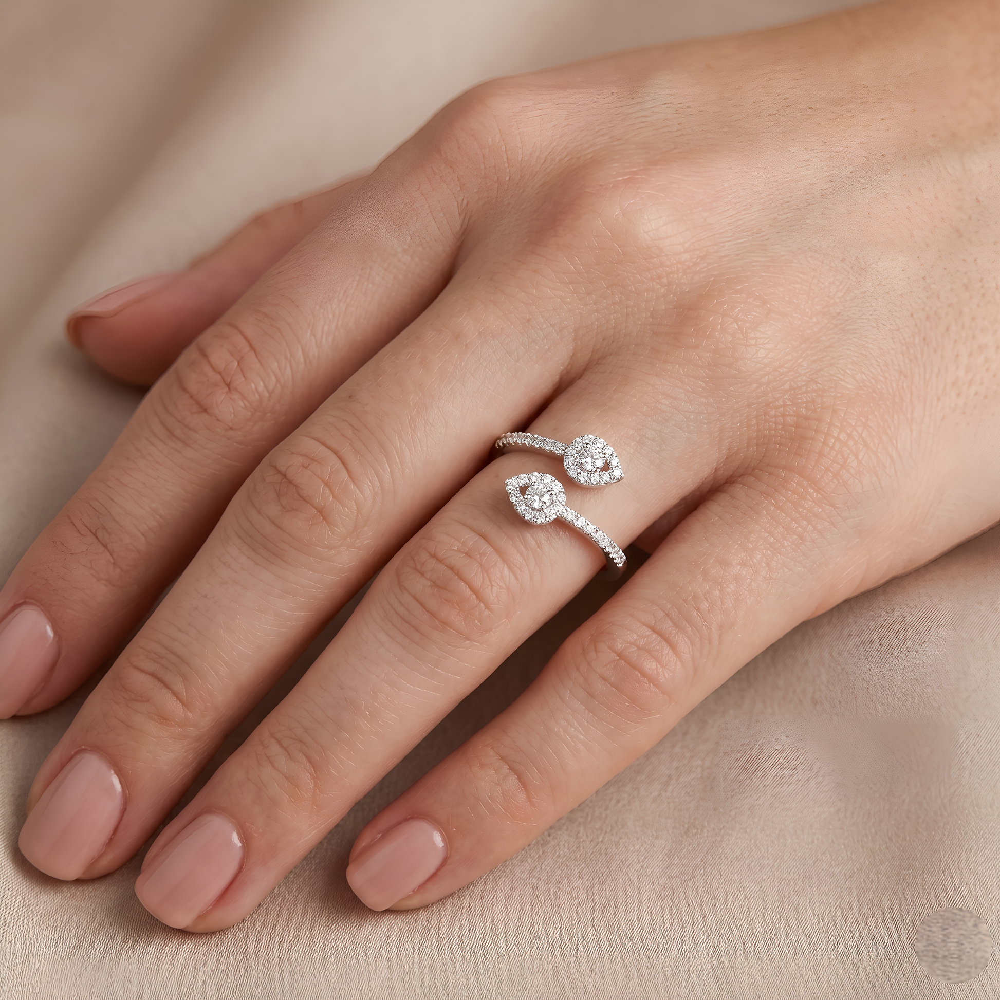 Silver ring with floral design on a hand against a beige background