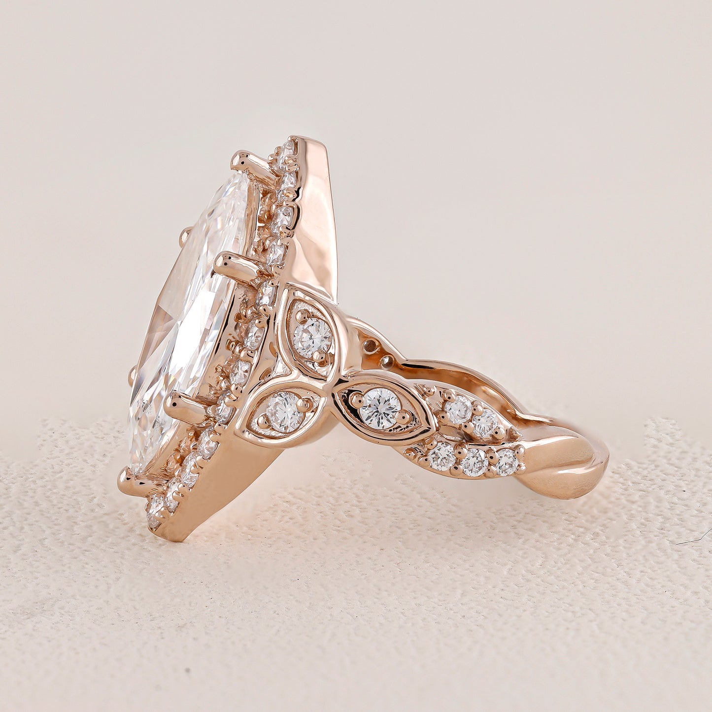 Rose gold ring with a large diamond and smaller diamonds on a light background