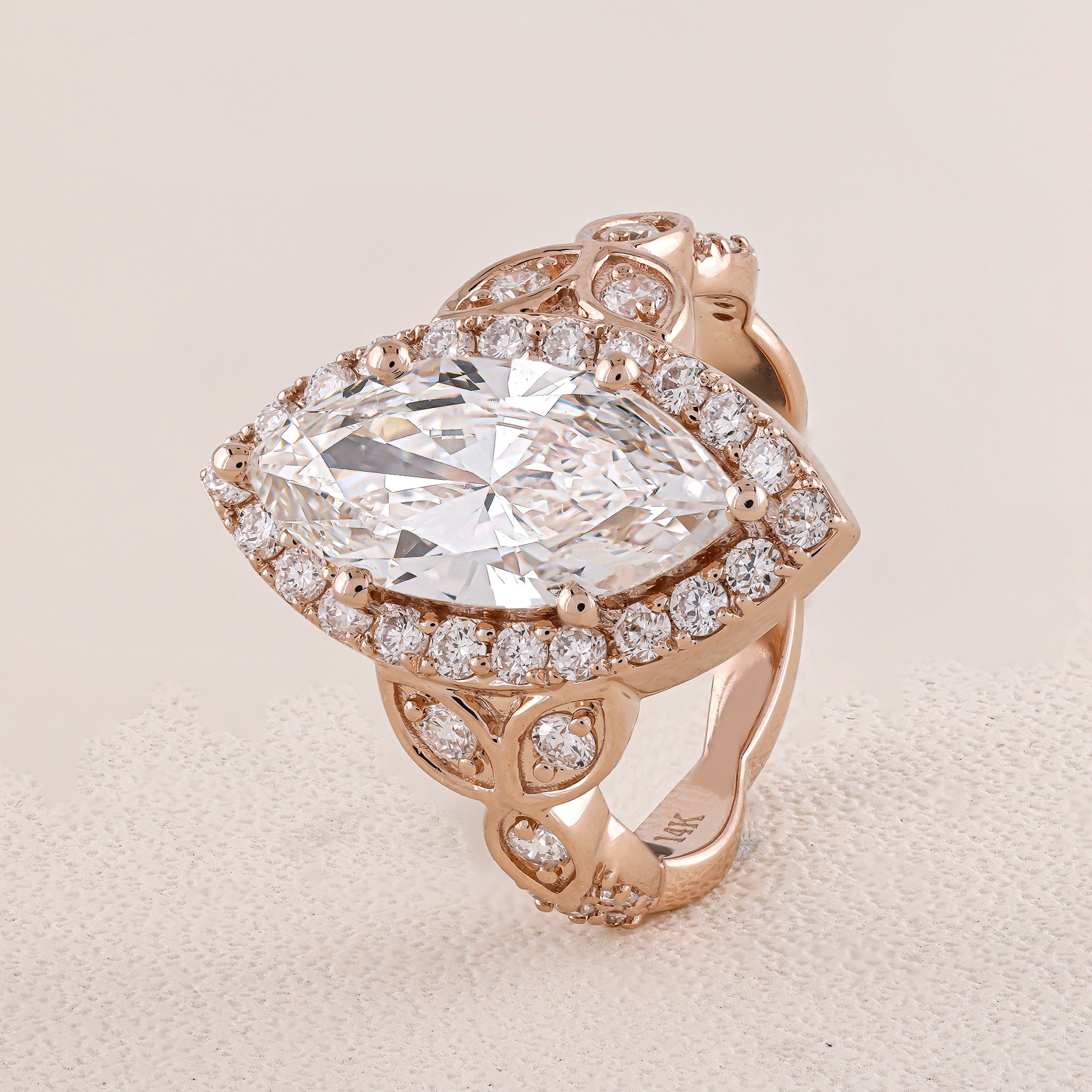 Rose gold ring with a large diamond and smaller diamonds on a light background