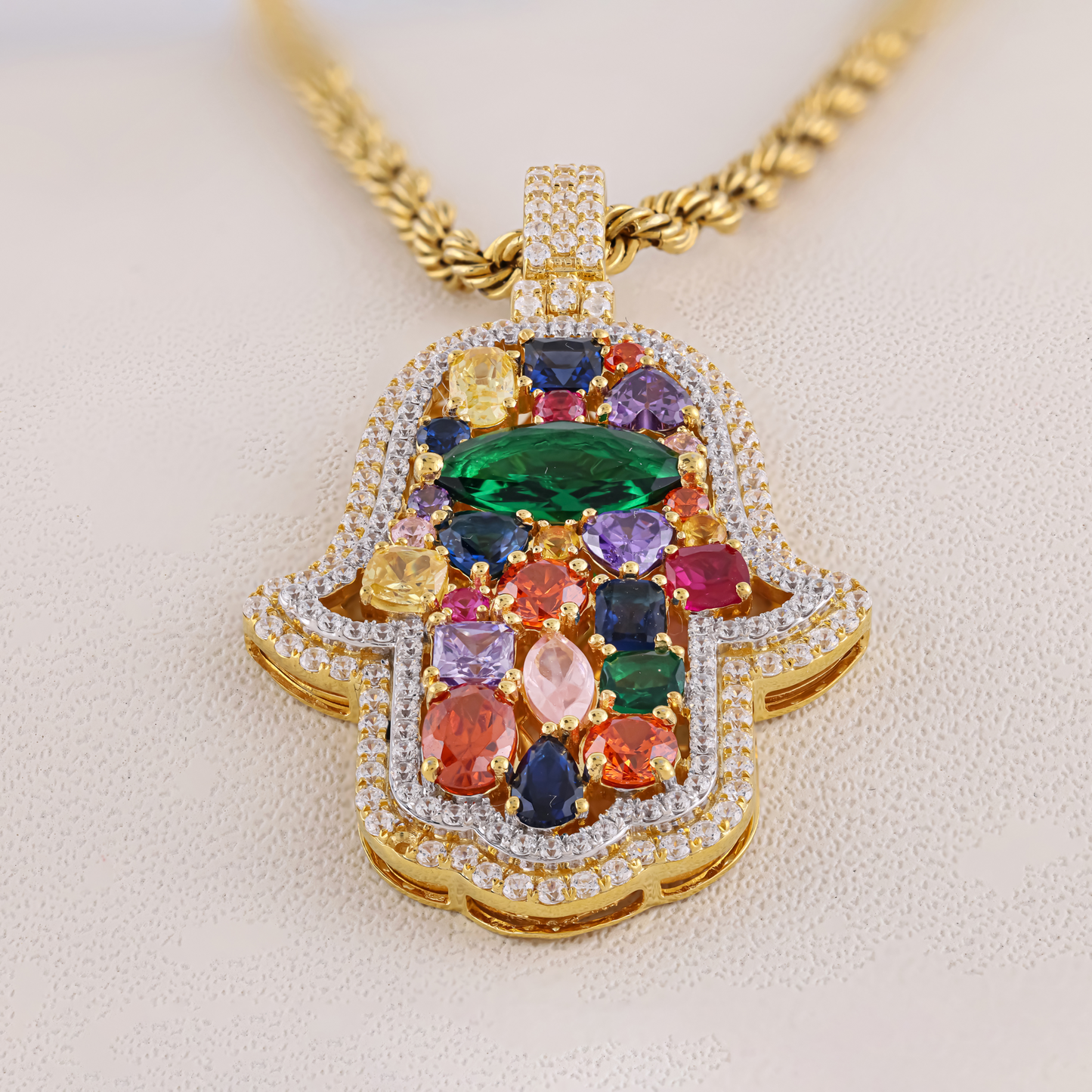 Multicolored gemstone pendant on a gold chain against a beige background