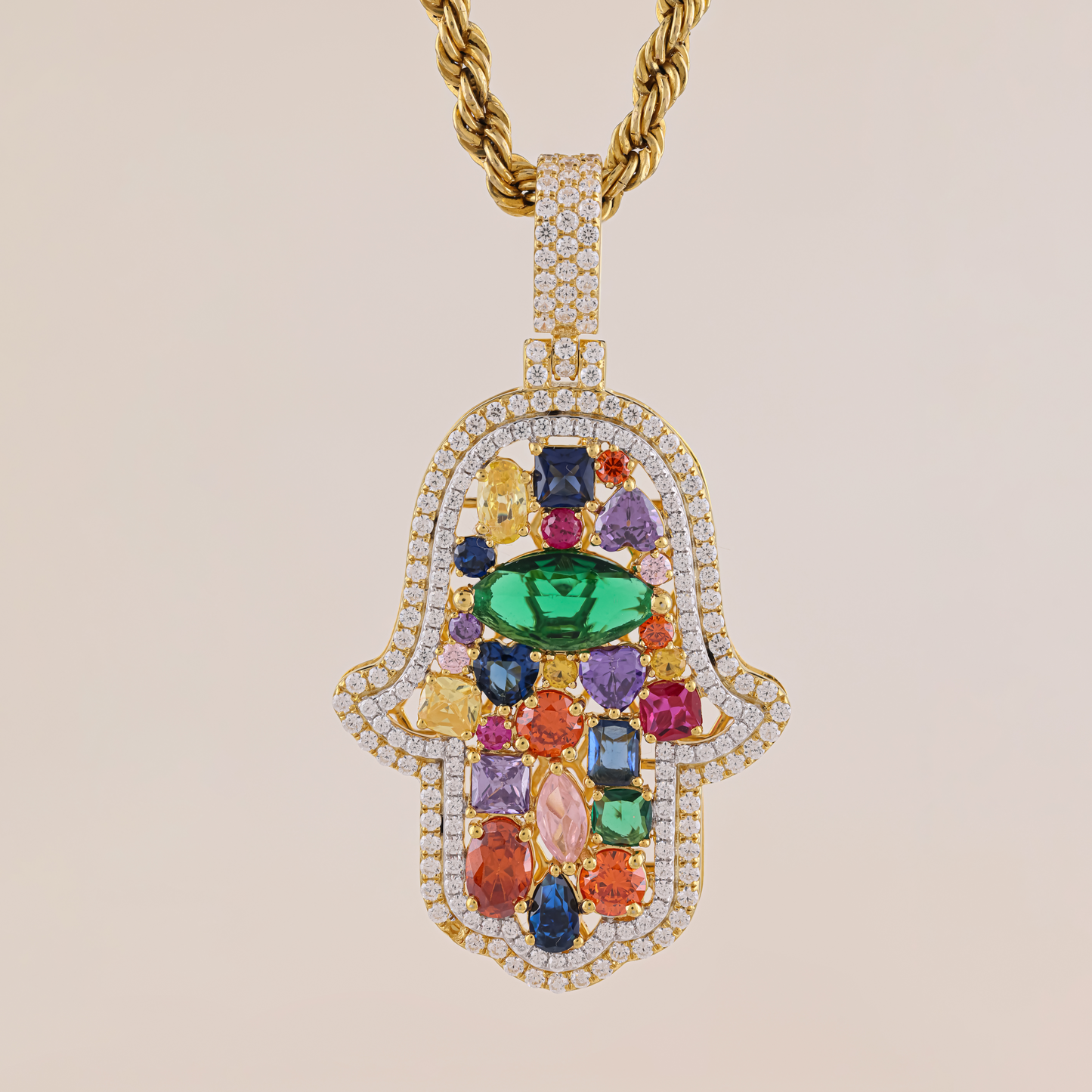 Jewelry pendant with colorful gemstones and gold chain on beige background