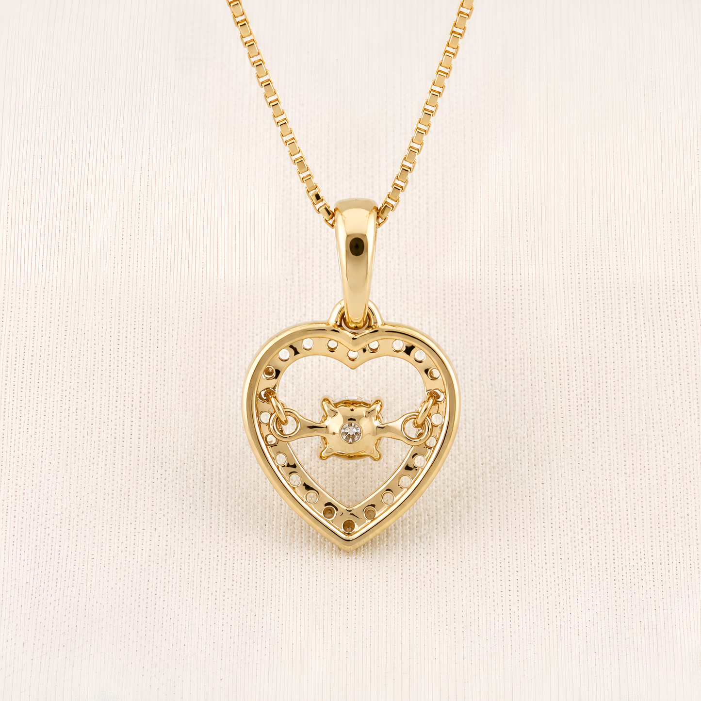 A gold heart-shaped pendant necklace with a small central lion motif, displayed on a textured off-white background.