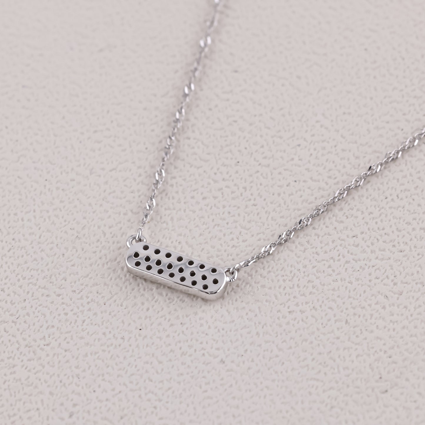 Silver necklace with a rectangular pendant on a light gray background