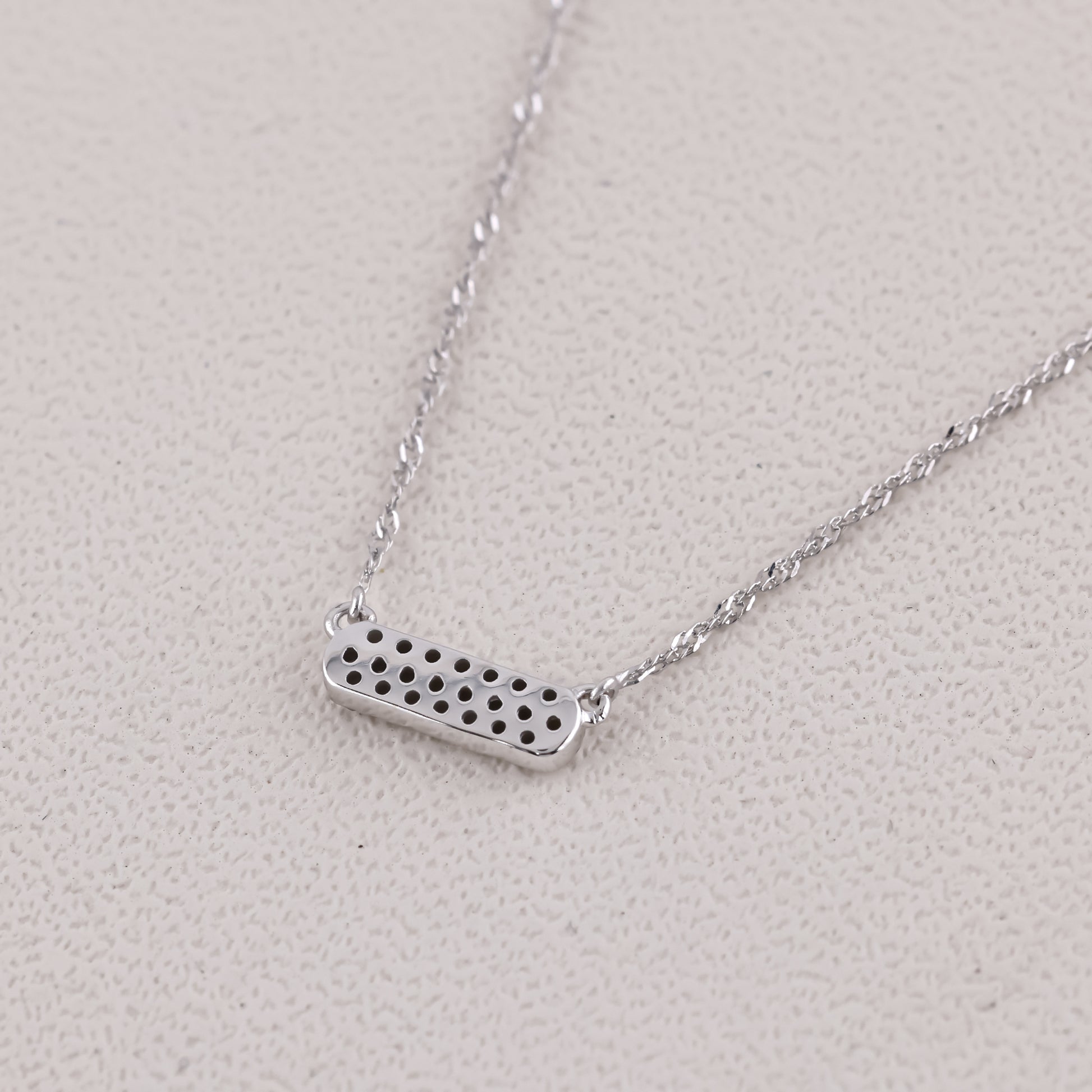 Silver necklace with a rectangular pendant on a light gray background