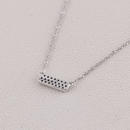 Silver necklace with a rectangular pendant on a light gray background