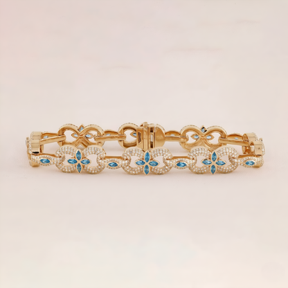 Gold bracelet with blue gemstones on a beige background