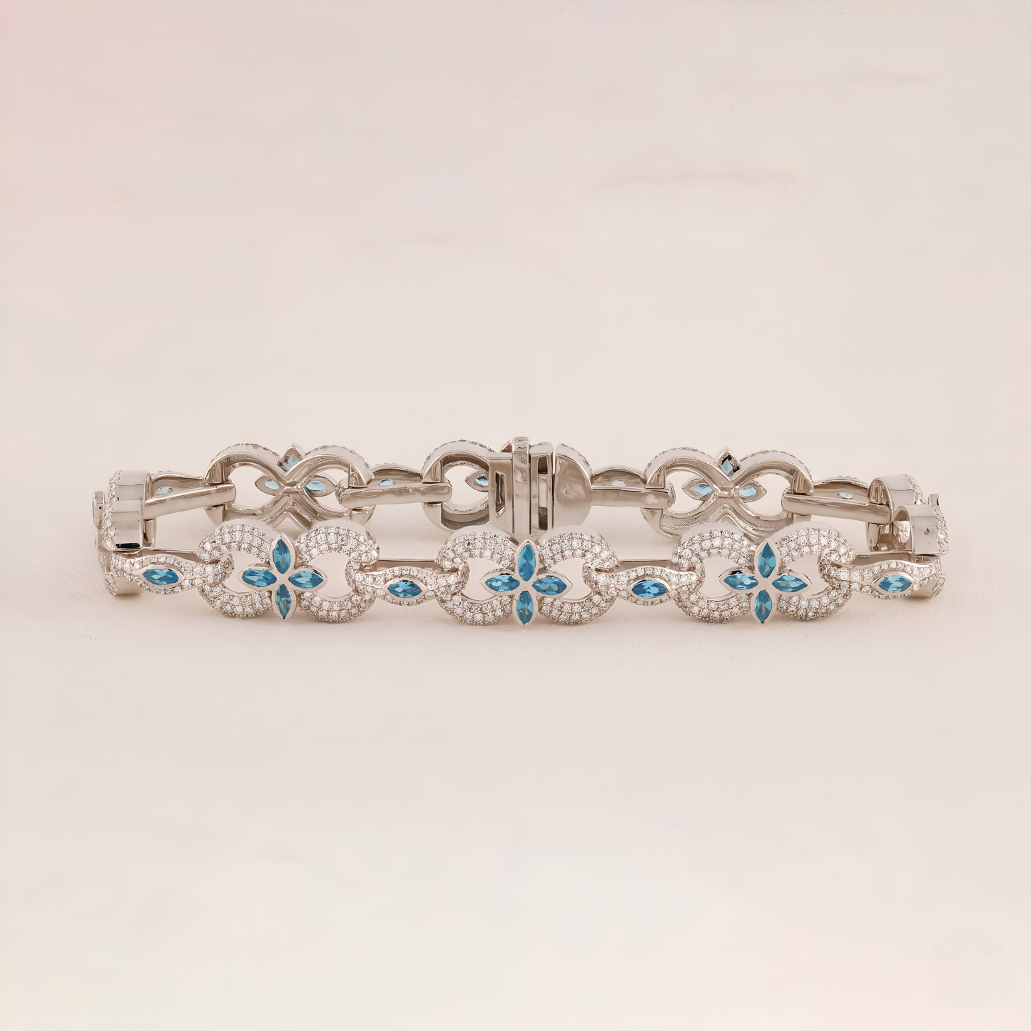 Silver bracelet with floral designs and blue stones on a light beige background