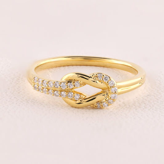 Gold ring with diamond accents on a light beige background
