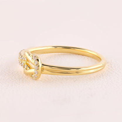 Gold ring with small diamonds on a light pink background