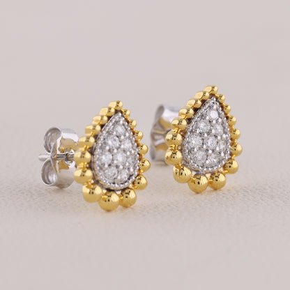Pair of gold and silver teardrop-shaped earrings on a light gray background