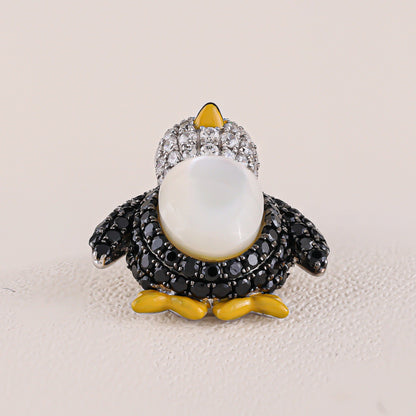 Penguin-shaped brooch with gemstones on a beige background