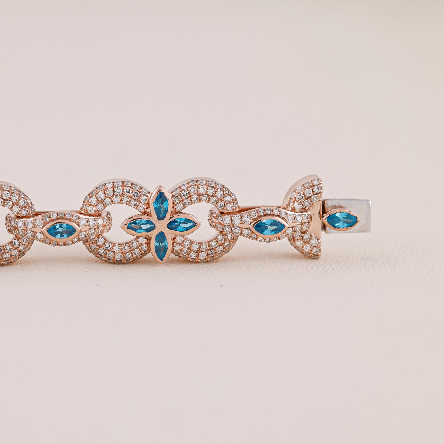 Rose gold bracelet with blue gemstones on a beige background