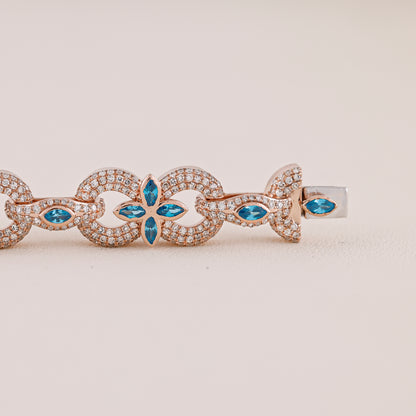 Rose gold bracelet with blue gemstones on a beige background
