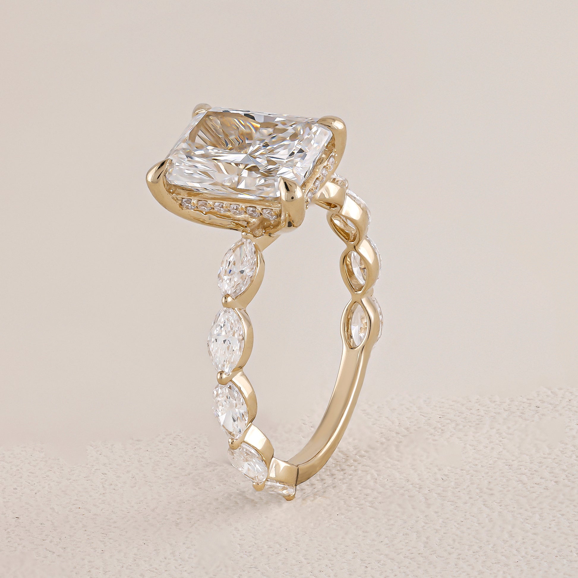 Gold ring with a large diamond and smaller diamonds on a beige background