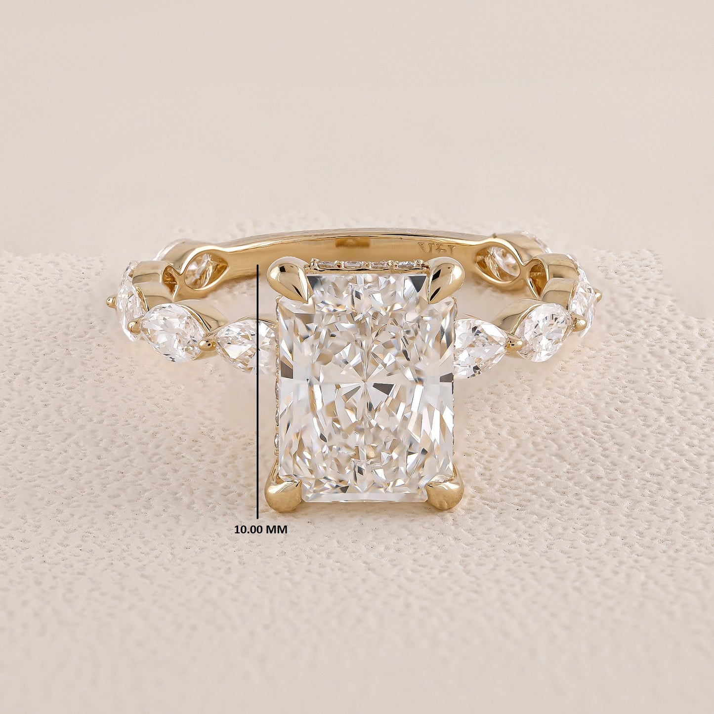 Gold ring with a large diamond and smaller side stones on a beige background